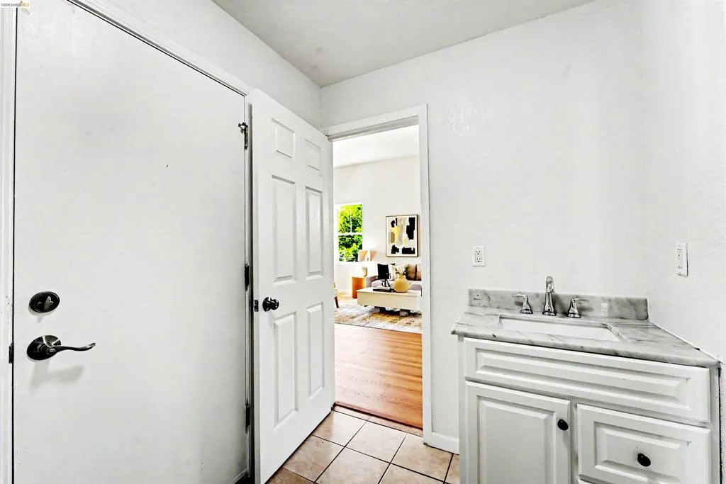 White paneled vanity with a polished countertop, undermount sink, and chrome faucet