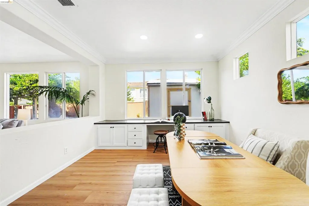 Bright interior space featuring wood-finish flooring, recessed lighting, and a built-in desk with white cabinetry and a dark countertop