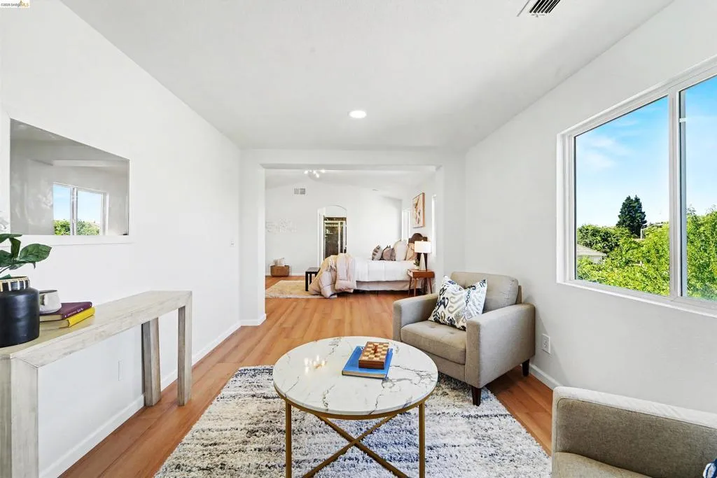 Bright living space featuring wood-finish flooring, a large window, recessed lighting, and an arched entryway to an additional room
