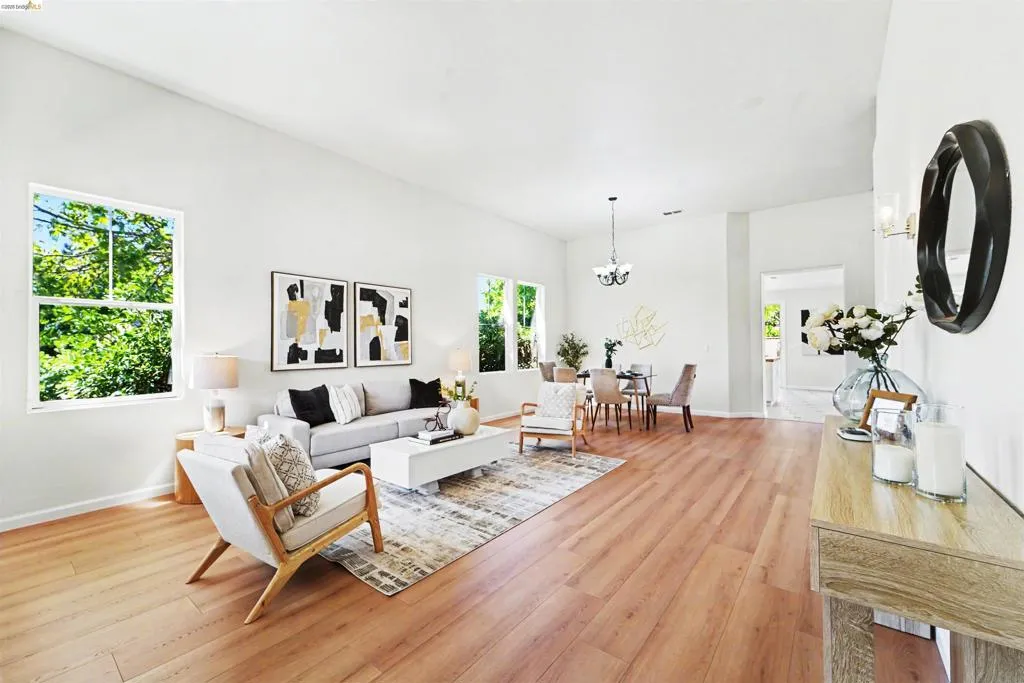 Expansive living area with wood-finish flooring, high ceilings, and multiple windows