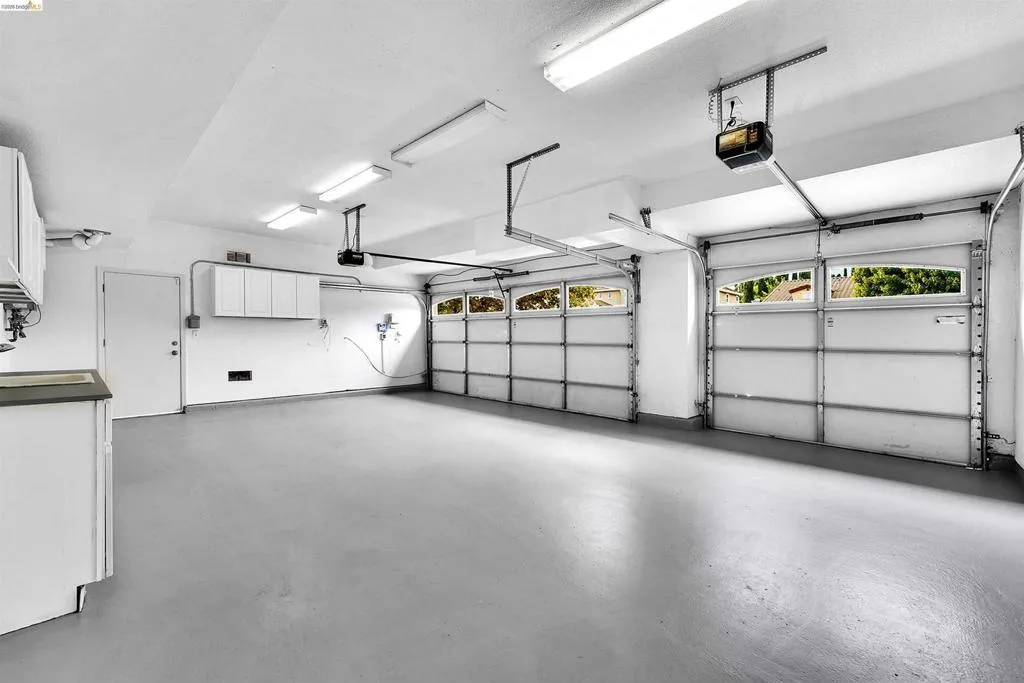 Spacious two-car garage featuring a gray-finished floor and bright overhead lighting