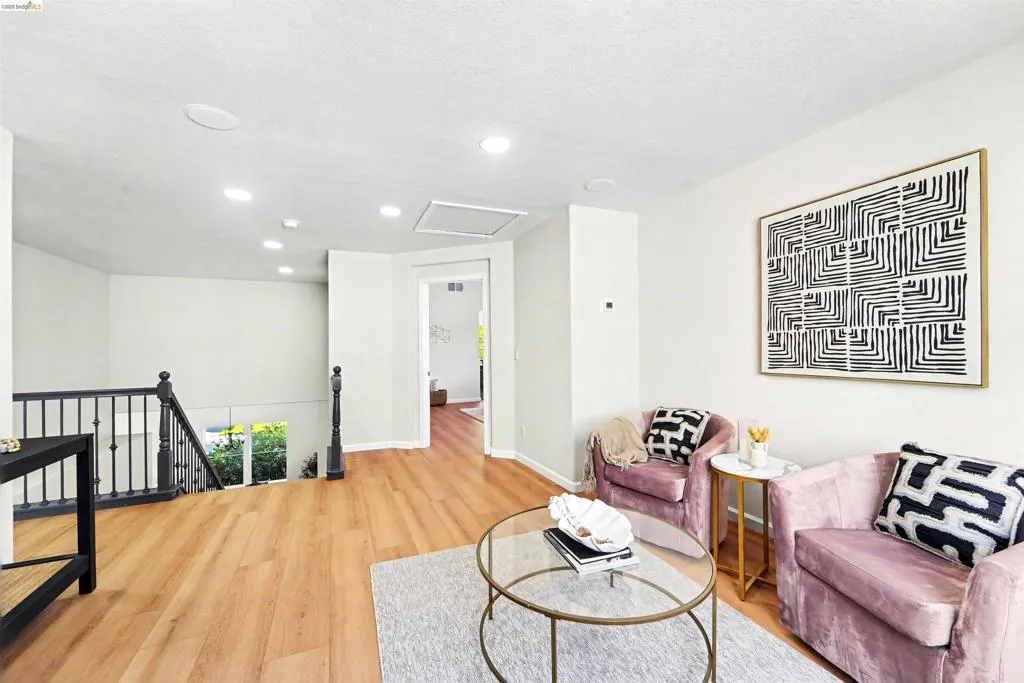 Upper-level landing featuring wood-finish flooring, recessed lighting, and a black spindle staircase with a dark wood newel post