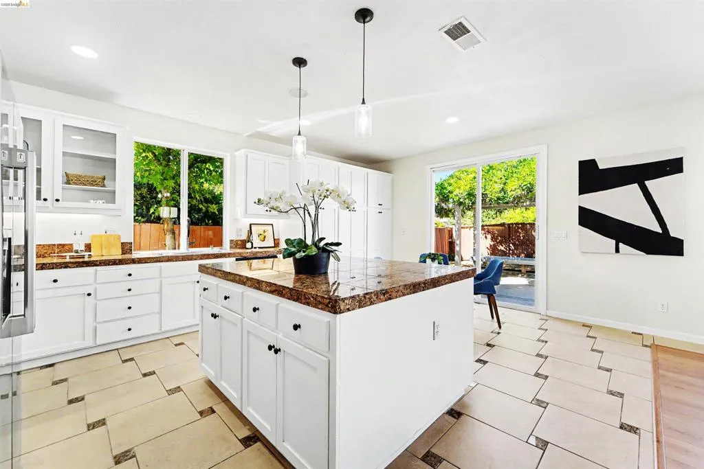 Gourmet kitchen featuring a central island, white cabinetry, integrated sink, and sliding glass door access to the exterior