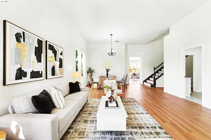Open-concept living area featuring hardwood flooring, white walls, and a chandelier-style light fixture in the dining space