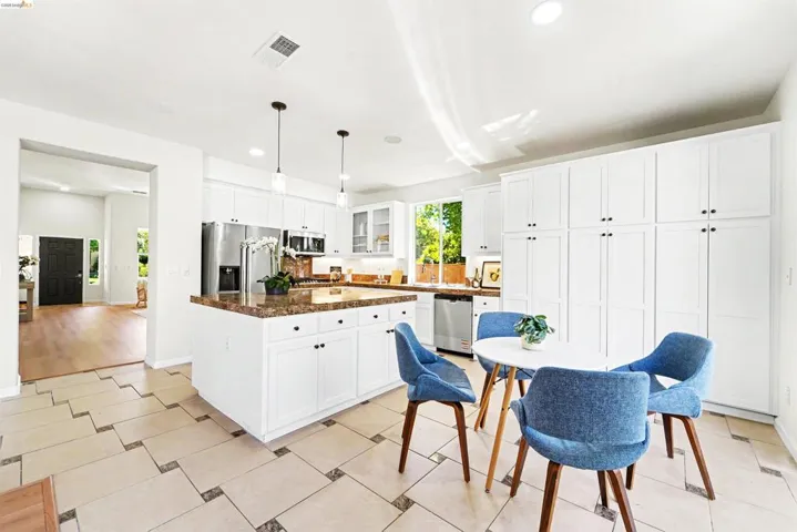Kitchen featuring white cabinetry, stainless steel appliances, a center island with a granite-style countertop, recessed lighting, and pendant fixtures