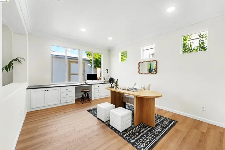 Dedicated workspace featuring built-in white cabinetry, a dark countertop, and multiple windows