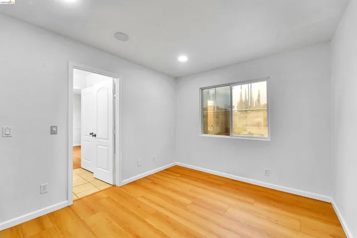 Room featuring wood-finish flooring, recessed lighting, and a white interior paint scheme