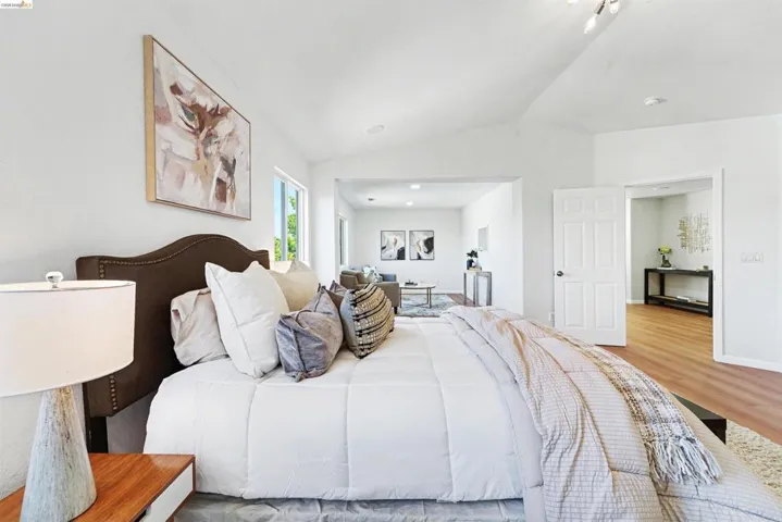 Spacious room with a vaulted ceiling, recessed lighting, and wood-finish flooring