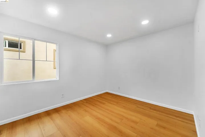Interior room featuring wood-finish flooring, white walls, and recessed lighting