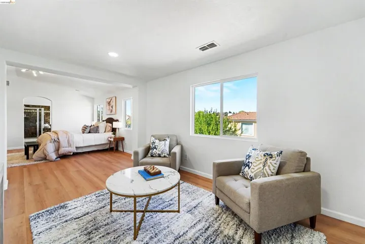 Open-concept living area with wood-finish flooring, recessed lighting, and bright white walls