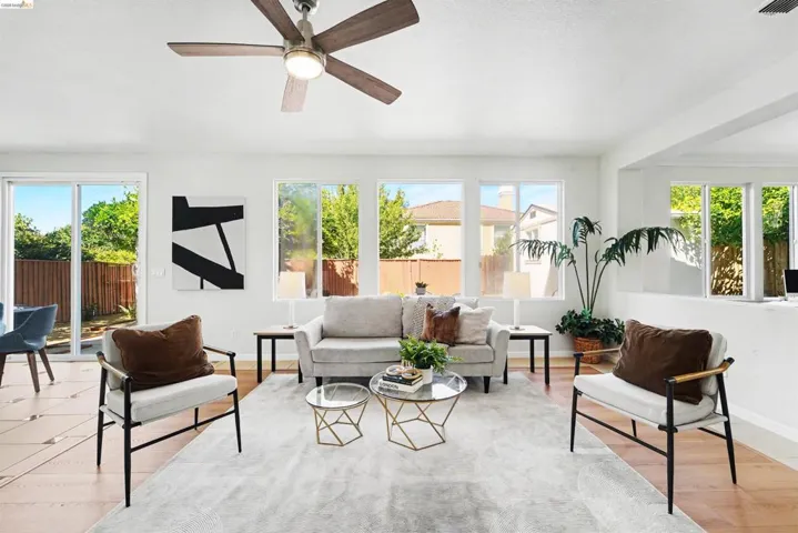 Living area featuring a ceiling fan, light wood-finish flooring, multiple windows, and a sliding glass door to the exterior