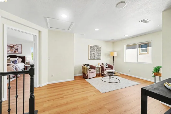 Open loft area featuring wood-finish flooring, recessed lighting, and a window for natural light
