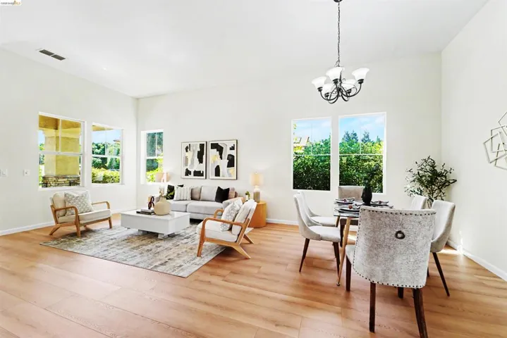 Bright, open-concept living and dining area featuring wood-finish flooring, recessed lighting, and expansive windows