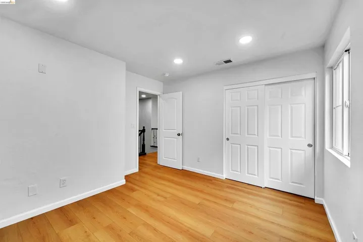 Room featuring wood-finish flooring, recessed lighting, white walls, and a window with a white frame