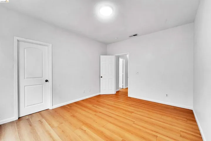 Room featuring wood-finish flooring, crisp white walls, white trim, a flush-mount ceiling light, and two white panel doors