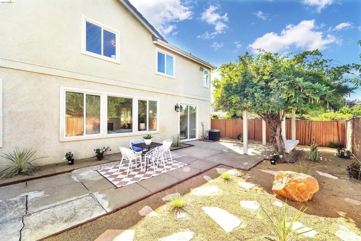 Rear exterior featuring a stucco facade, multiple windows, and a sliding glass door