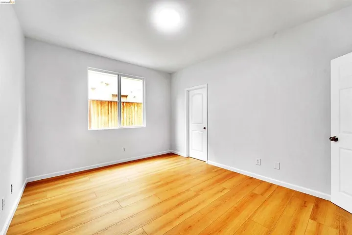 Bright interior space featuring wood-finish flooring, white walls, and a large window