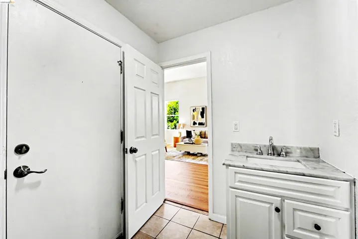 White paneled vanity with a polished countertop, undermount sink, and chrome faucet
