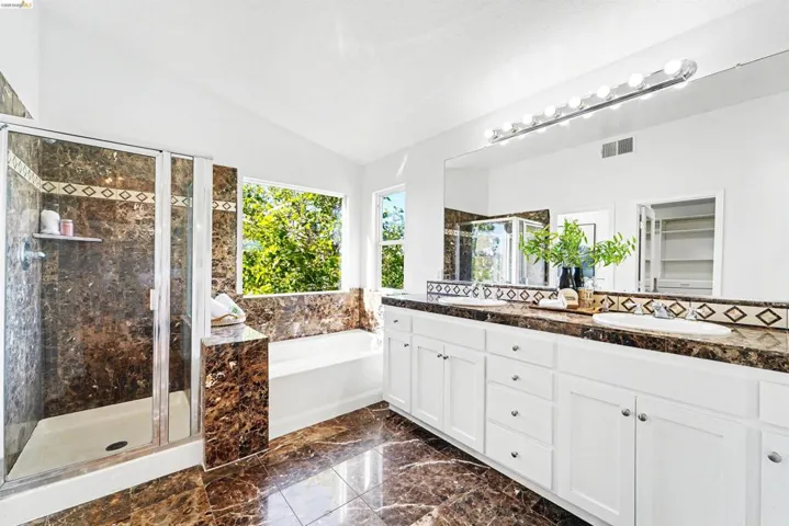 Spacious bathroom with marble-finish tile flooring, a large glass-enclosed shower, and a built-in soaking tub