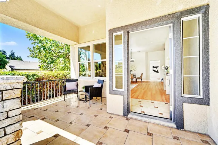 Covered entry porch featuring stone veneer columns, wrought iron railing, and patterned tile flooring