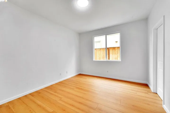 Room featuring light wood-finish flooring, white walls, and a single window with white trim