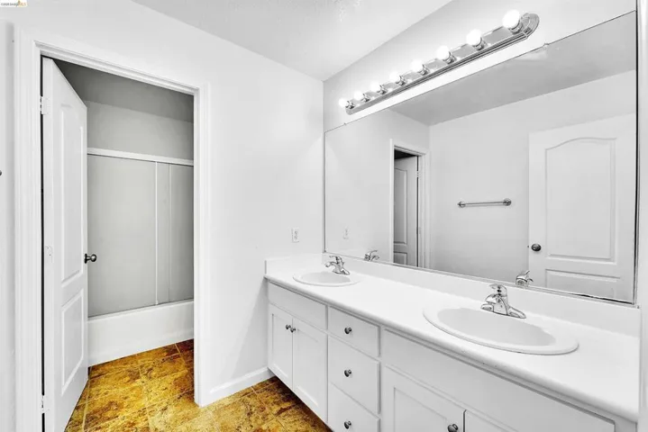 White double vanity with dual undermount sinks, chrome fixtures, and a large wall-mounted mirror