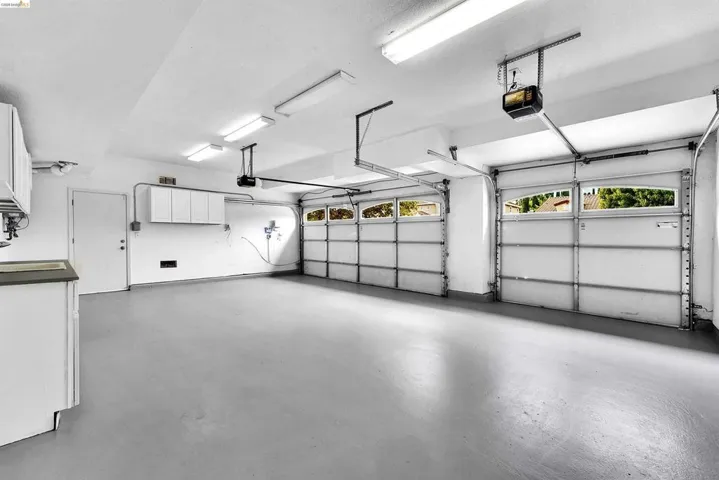 Spacious two-car garage featuring a gray-finished floor and bright overhead lighting