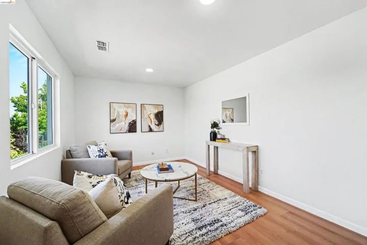 Living area featuring abundant natural light, wood-finish flooring, crisp white walls, and recessed lighting