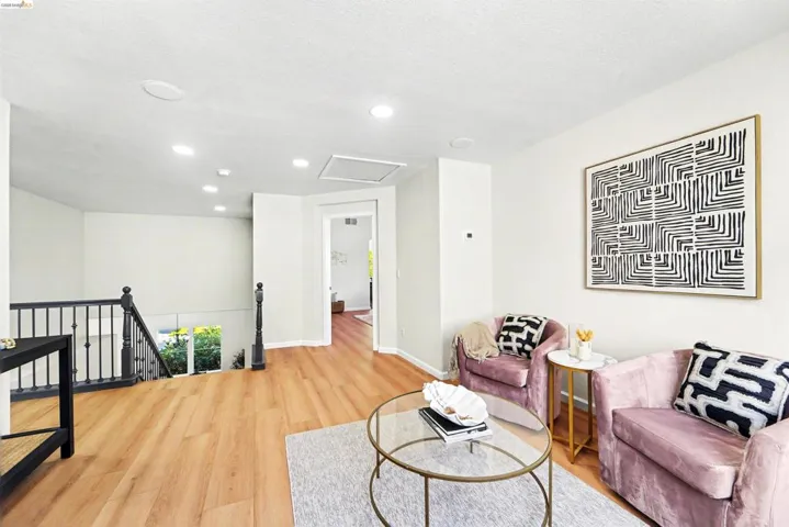 Upper-level landing featuring wood-finish flooring, recessed lighting, and a black spindle staircase with a dark wood newel post