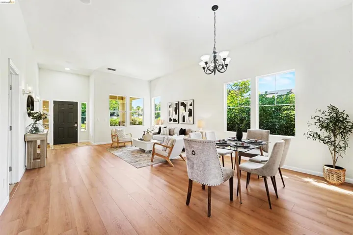 Open concept living area featuring wood-finish flooring, high ceilings, and abundant natural light from multiple windows