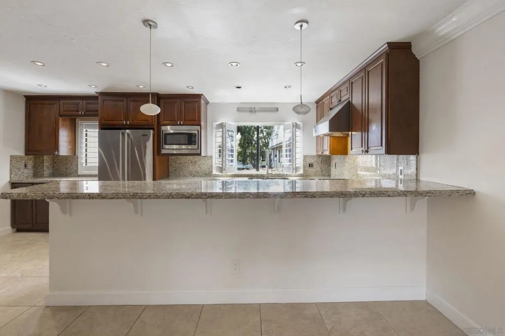 Open Floor Plan Kitchen with Kitchen Island Bar Area Dining, with Upgraded Viking Kitchen Appliances, Baseboards & Crown Moulding, and Custom Plantation Shutters.