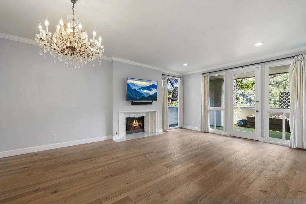 Huge Primary Bedroom with and Gas/Wood Burning Fireplace, Floor to Ceiling Windows and Doors Opening to the Large Outdoor Covered Terrace/Balcony offering Ocean Breezes and Views of Mount Soledad and Trees.