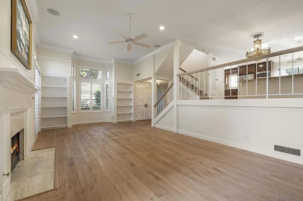 Living Room, Offering Vaulted Ceilings, Custom Plantation Shutters, Floor-Ceiling Windows & Doors, Custom Enlarged Crown Moulding & Baseboards, Wood Burning/Gas Start Fireplace, Custom Audio and Lighting in Walls & Ceiling.