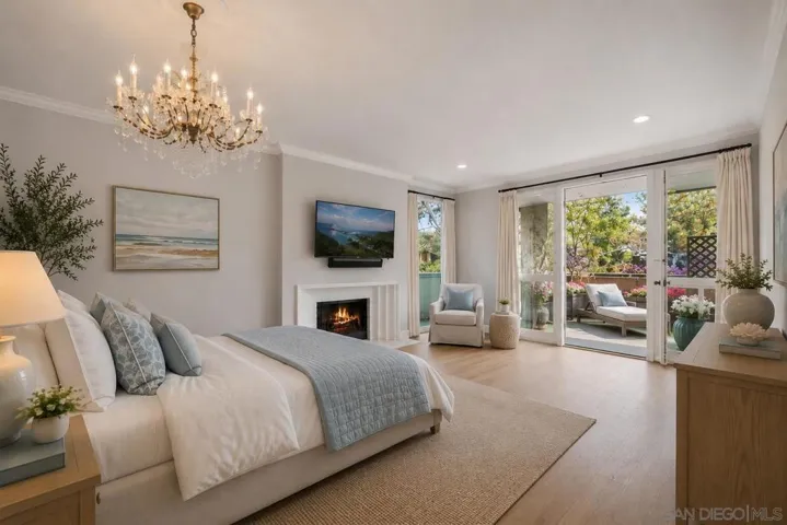 Huge Primary Bedroom with and Gas/Wood Burning Fireplace, Floor to Ceiling Windows and Doors Opening to the Large Outdoor Covered Terrace/Balcony offering Ocean Breezes and Views of Mount Soledad and Trees. Virtually Staged.