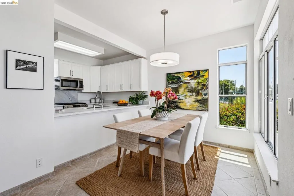 Dining area featuring an open kitchen pass-through, large windows, recessed lighting, and tile flooring