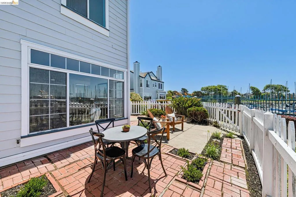 Patio featuring brick pavers and a white picket fence