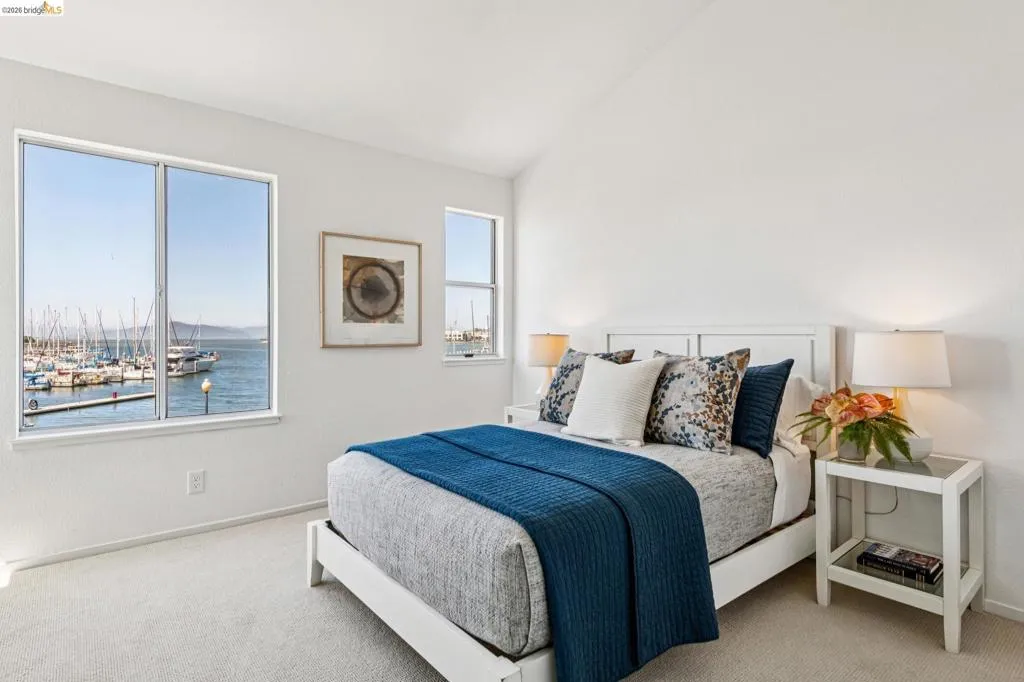 Bedroom featuring two windows offering harbor and marina scenery