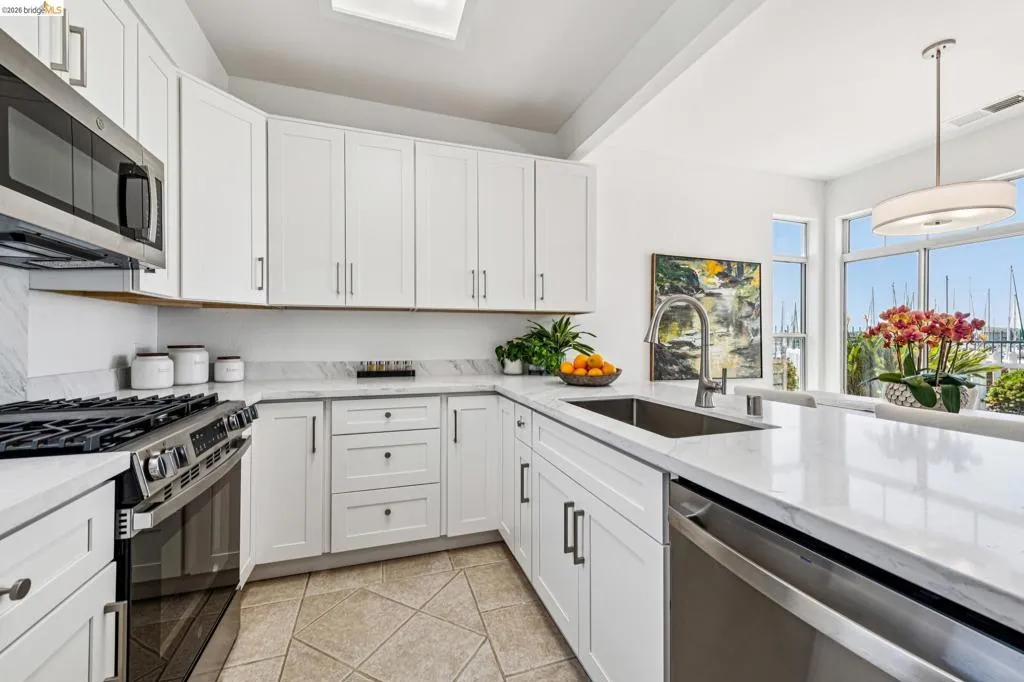 Modern kitchen featuring white shaker cabinetry, stainless steel appliances, and light-toned countertops