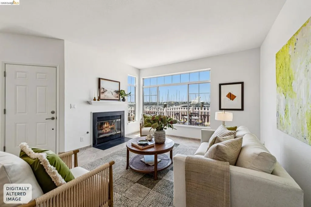 Living area featuring a fireplace with a black surround and white mantelpiece, large windows overlooking a marina, and light-colored walls