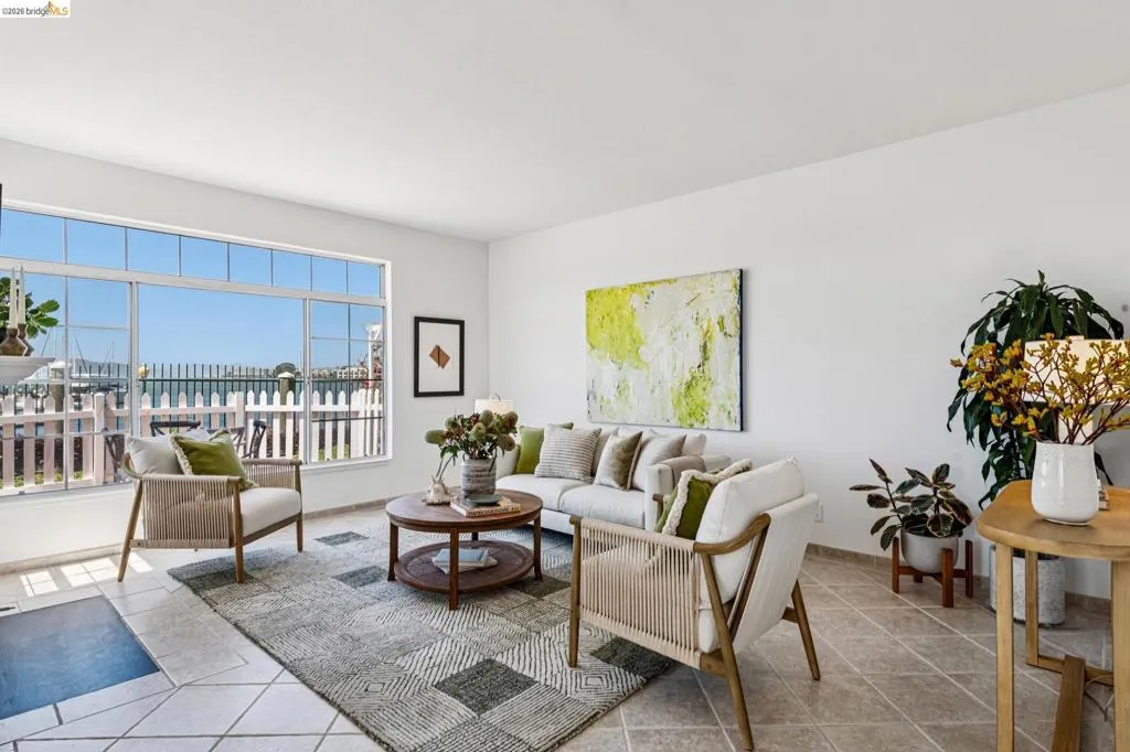 Bright living area featuring expansive windows with water views, tile flooring, and white painted walls