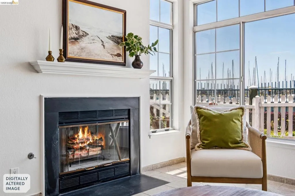 Fireplace with a black surround and hearth, featuring a white mantel, positioned alongside large windows