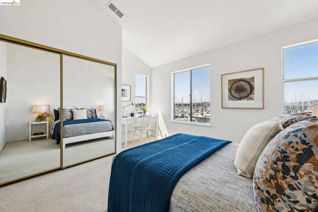 Bedroom featuring a vaulted ceiling and dual windows overlooking a marina