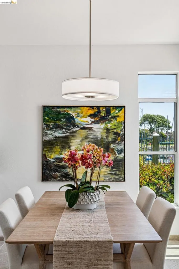 Bright interior space featuring a drum pendant light fixture, light wood-finish flooring, and a large window offering exterior scenery