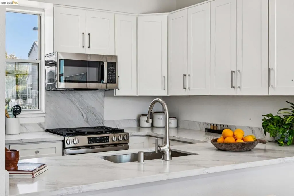 Kitchen featuring white shaker cabinetry, stainless steel appliances, a gas range, and a single-basin sink with a gooseneck faucet