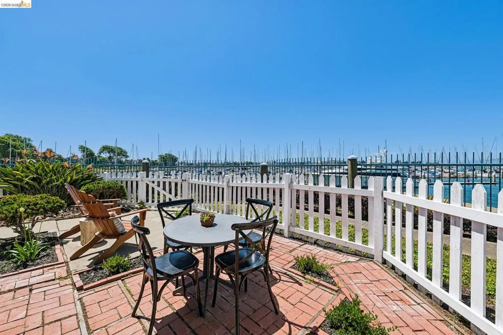 Brick paver patio with a white picket fence bordering the marina