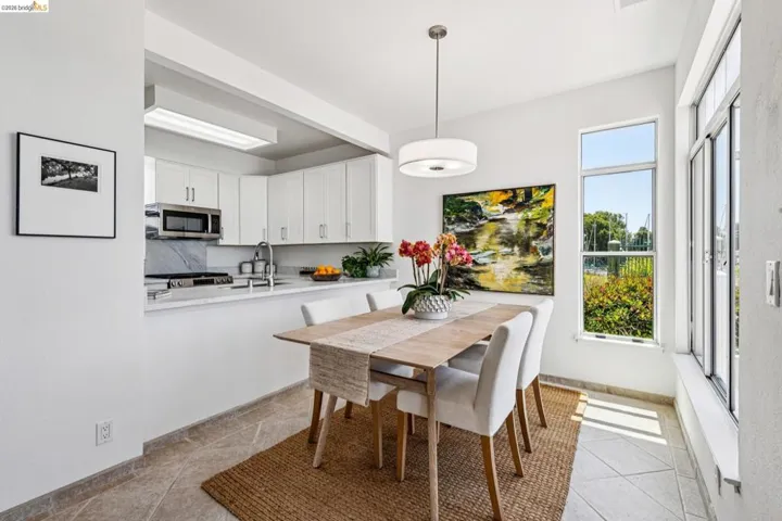 Dining area featuring an open kitchen pass-through, large windows, recessed lighting, and tile flooring