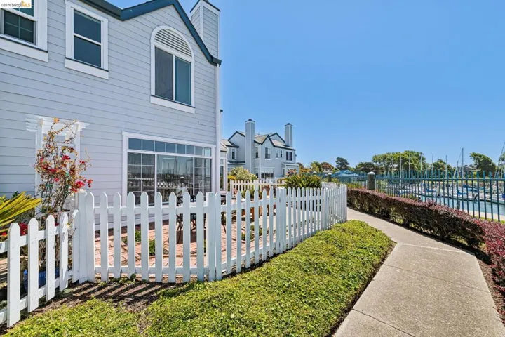 Waterfront property featuring a private patio, white picket fence, sliding glass doors, and a concrete pathway