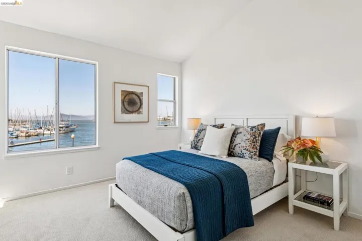 Bedroom featuring two windows offering harbor and marina scenery