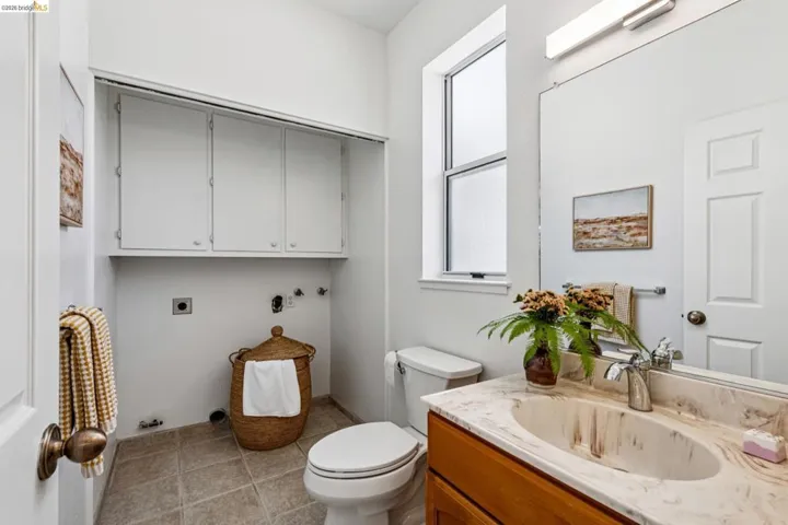 Bathroom featuring a wood-finish vanity with an integrated sink and stone-finish countertop, a mounted mirror, and a window