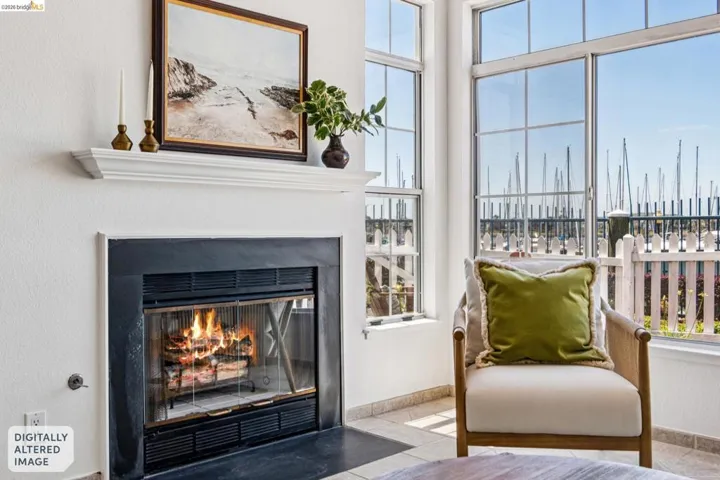Fireplace with a black surround and hearth, featuring a white mantel, positioned alongside large windows